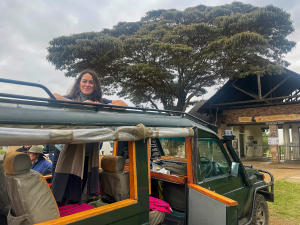 Green safari vehicle with people in front of Narok County Government Oloololo Gate entrance.